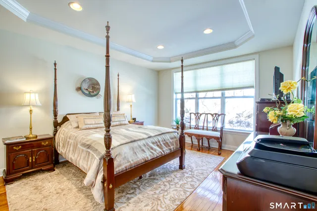 a bedroom with a bed table flowerpot and window