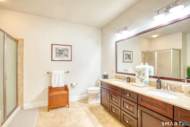 a spacious bathroom with a double vanity sink a large mirror and a toilet