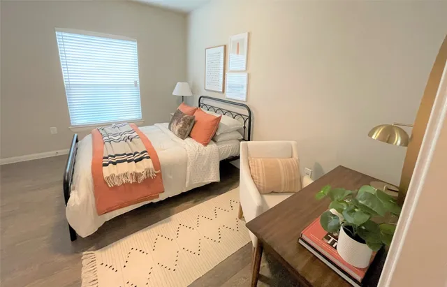 a bedroom with a bed and a dresser with wooden floor