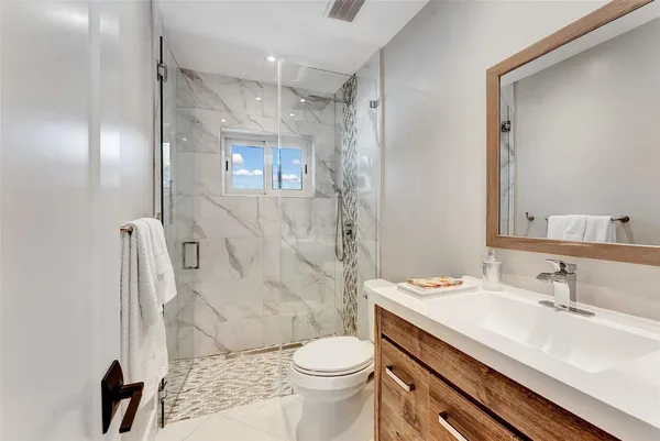 a bathroom with a sink toilet a mirror and shower