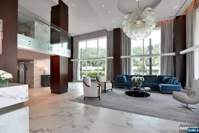a living room with furniture large windows and a chandelier