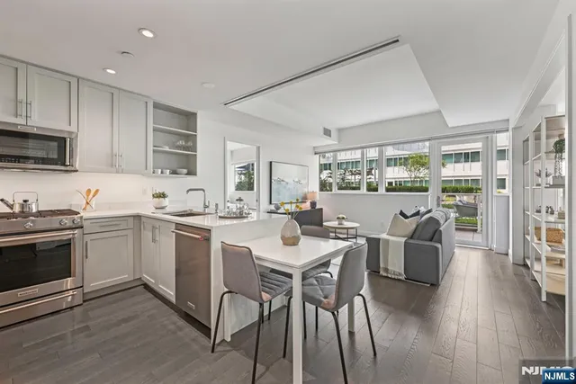 a kitchen with stainless steel appliances granite countertop a stove a sink dishwasher a dining table and chairs with wooden floor