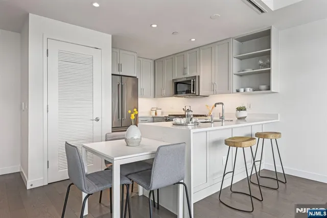 a kitchen with stainless steel appliances granite countertop a sink a stove a refrigerator and island with wooden floor