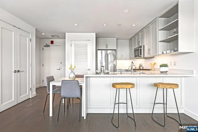a kitchen with stainless steel appliances granite countertop a dining table chairs and white cabinets