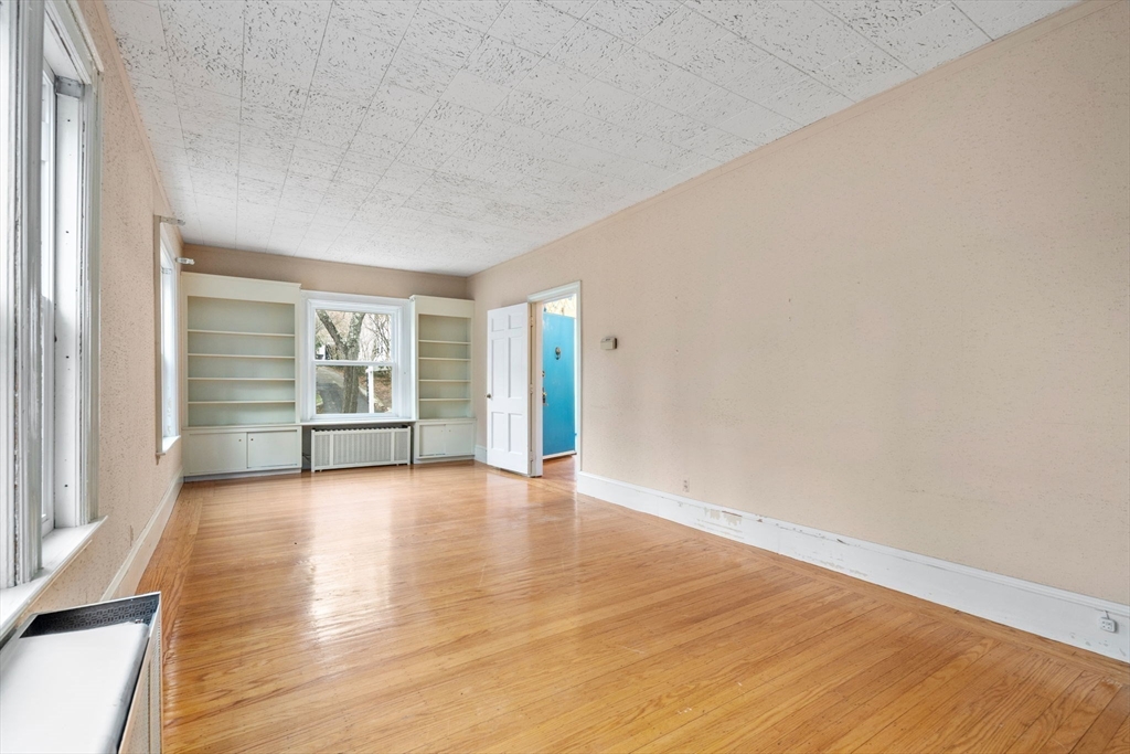 187 Clark Road Brookline, MA 02445 - Photo 15 of 40 a view of an empty room with a window and wooden floor