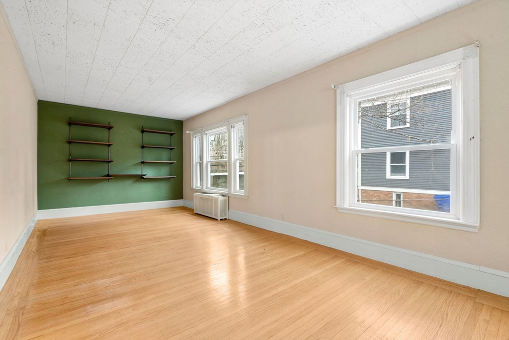 187 Clark Road Brookline, MA 02445 - Photo 6 of 40 a view of an empty room with a window and wooden floor