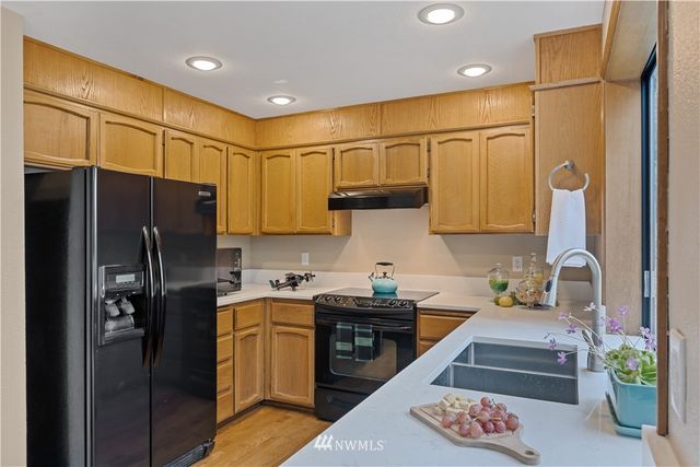 a kitchen with stainless steel appliances granite countertop a refrigerator a sink and white cabinets