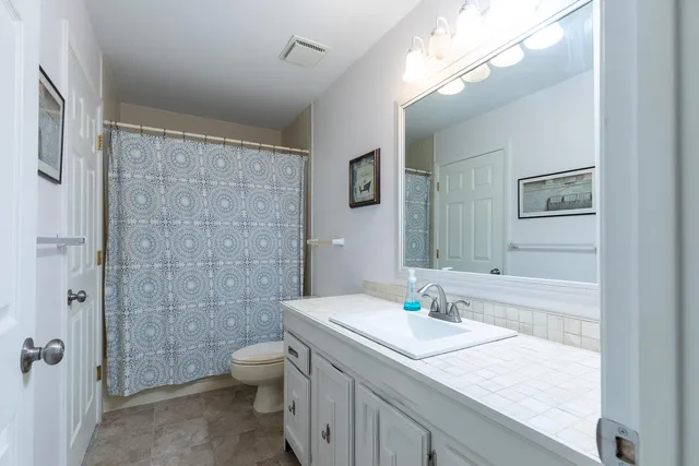 a bathroom with a granite countertop sink a toilet and shower