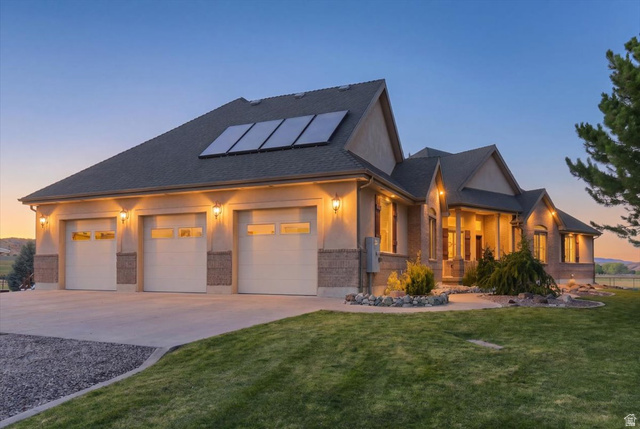 11290 South Southfield Road Mayfield, UT 84643 - Photo 3 of 103 Stucco and brick exterior with a three-car garage, solar panels, a covered entry, and landscaped rock accents