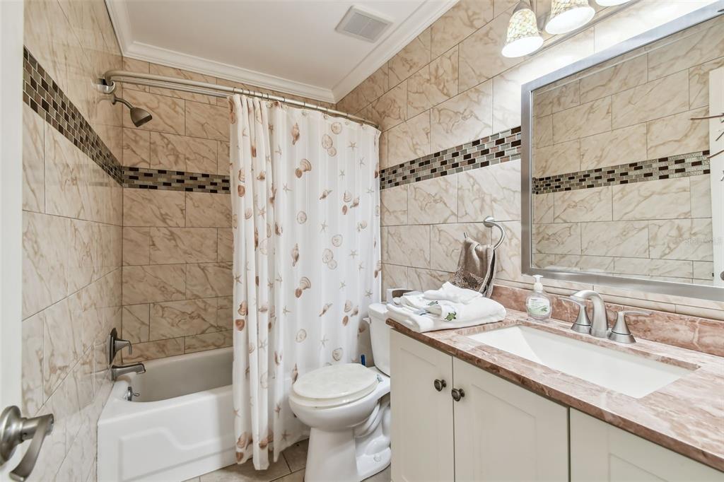 7200 Ulmerton Road, Unit E3 Largo, FL 33771 - Photo 15 of 26 a bathroom with a granite countertop sink a toilet a mirror a bathtub and shower