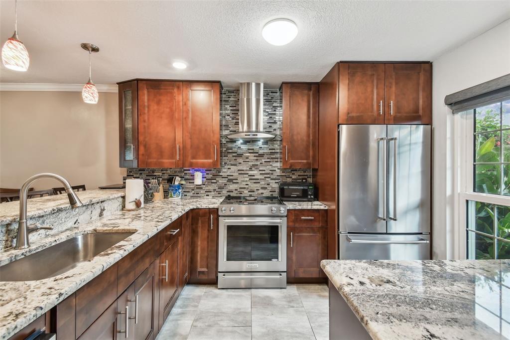 7200 Ulmerton Road, Unit E3 Largo, FL 33771 - Photo 6 of 26 a kitchen with stainless steel appliances granite countertop wooden cabinets a sink and a stove