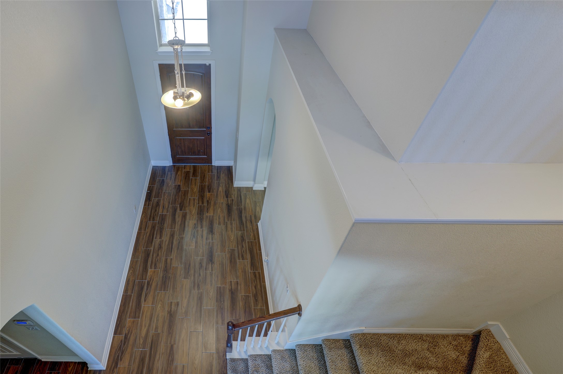 409 Betony Loop Buda, TX 78610 - Photo 15 of 38 A grand entrance welcomes guests with striking wood flooring and a classic chandelier, leading to a carpeted staircase.