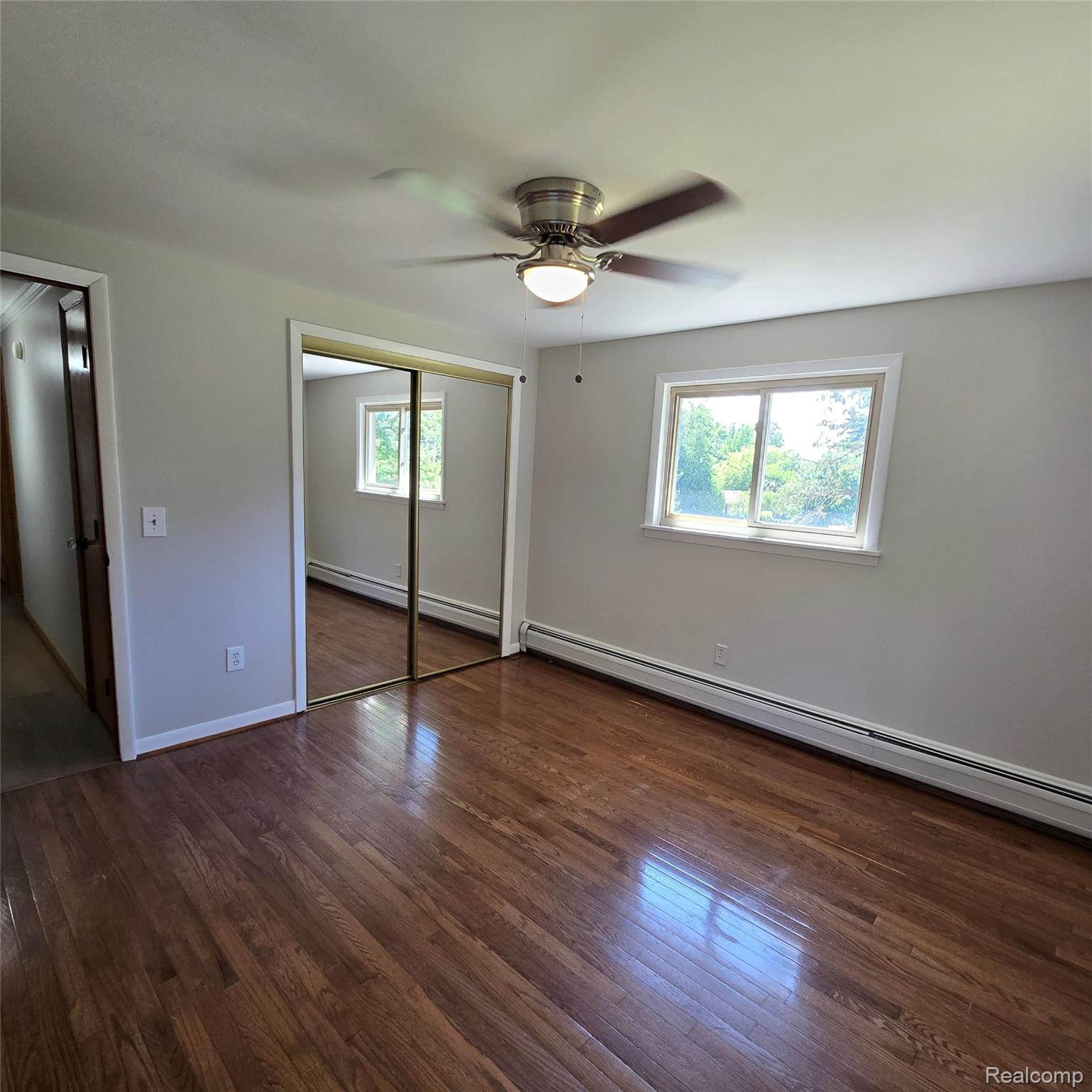 311 Nevada Avenue Rochester, MI 48309 - Photo 35 of 70 Spacious room featuring wood-finish flooring, a ceiling fan with integrated lighting, mirrored closet doors, and two windows with white trim