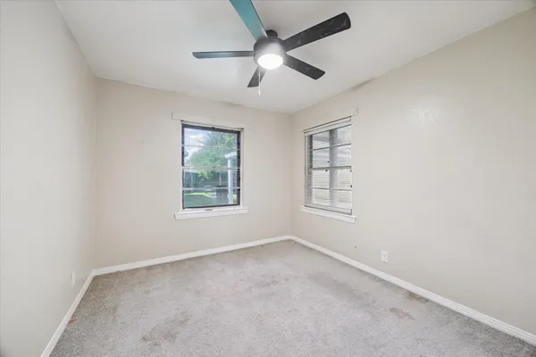 an empty room with a window and a ceiling fan