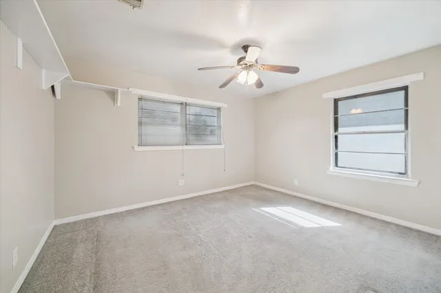 an empty room with windows and fan