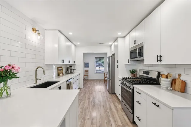 a kitchen with granite countertop a sink a stove refrigerator and cabinets