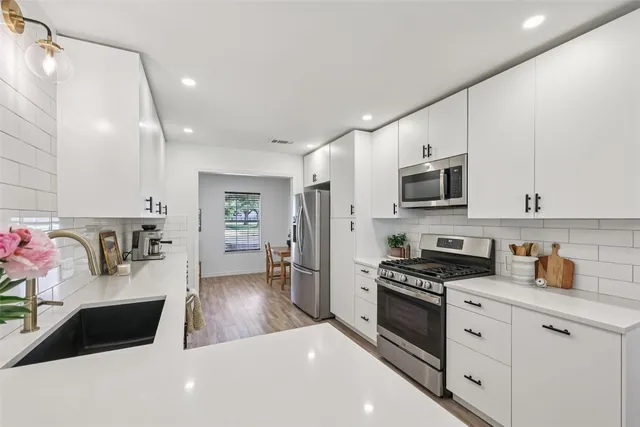 a kitchen with stainless steel appliances a refrigerator sink and wooden floor