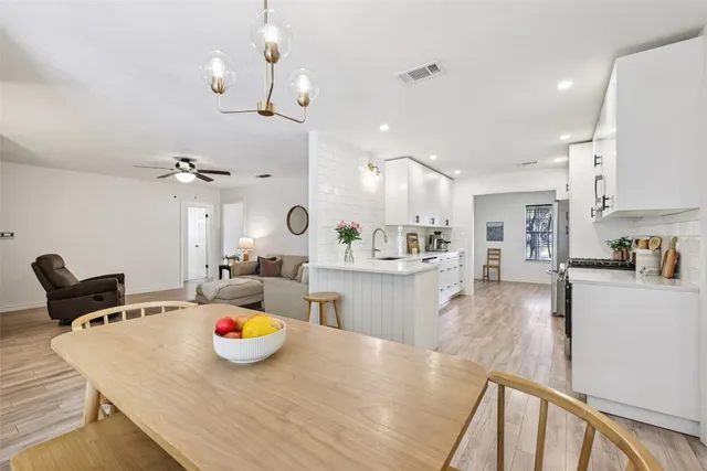 a dining room with wooden floor a chandelier a wooden table and chairs
