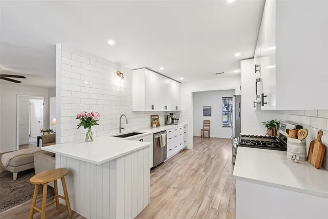 a kitchen with stainless steel appliances a white stove top oven a sink dishwasher and a refrigerator with wooden floor