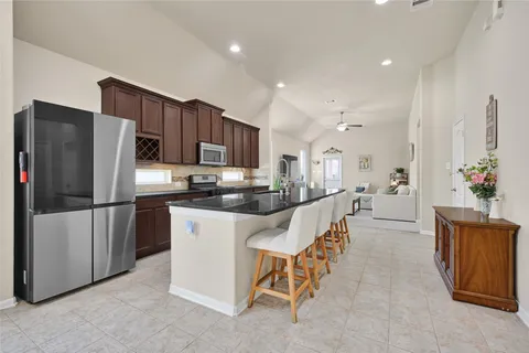 a kitchen with stainless steel appliances a refrigerator a stove a sink a dining table and chairs
