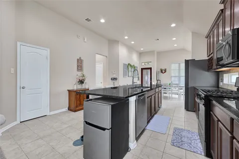 a kitchen with stainless steel appliances granite countertop a stove top oven a sink a counter space and cabinets