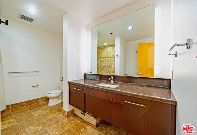 a bathroom with a granite countertop sink toilet and shower
