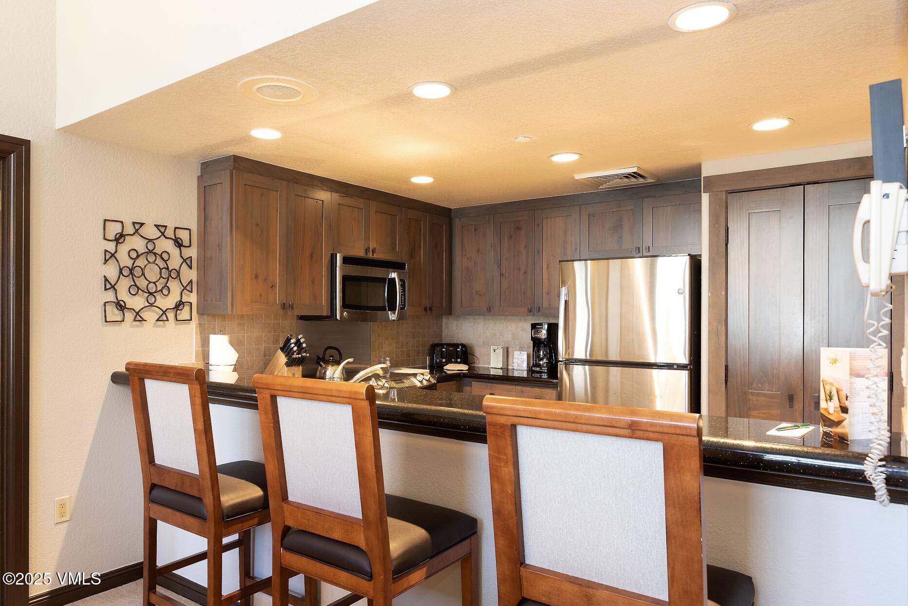 210 Offerson Road, Unit R203 WEEK 14 Beaver Creek, CO 81620 - Photo 7 of 31 a kitchen with stainless steel appliances a stove a sink refrigerator and microwave
