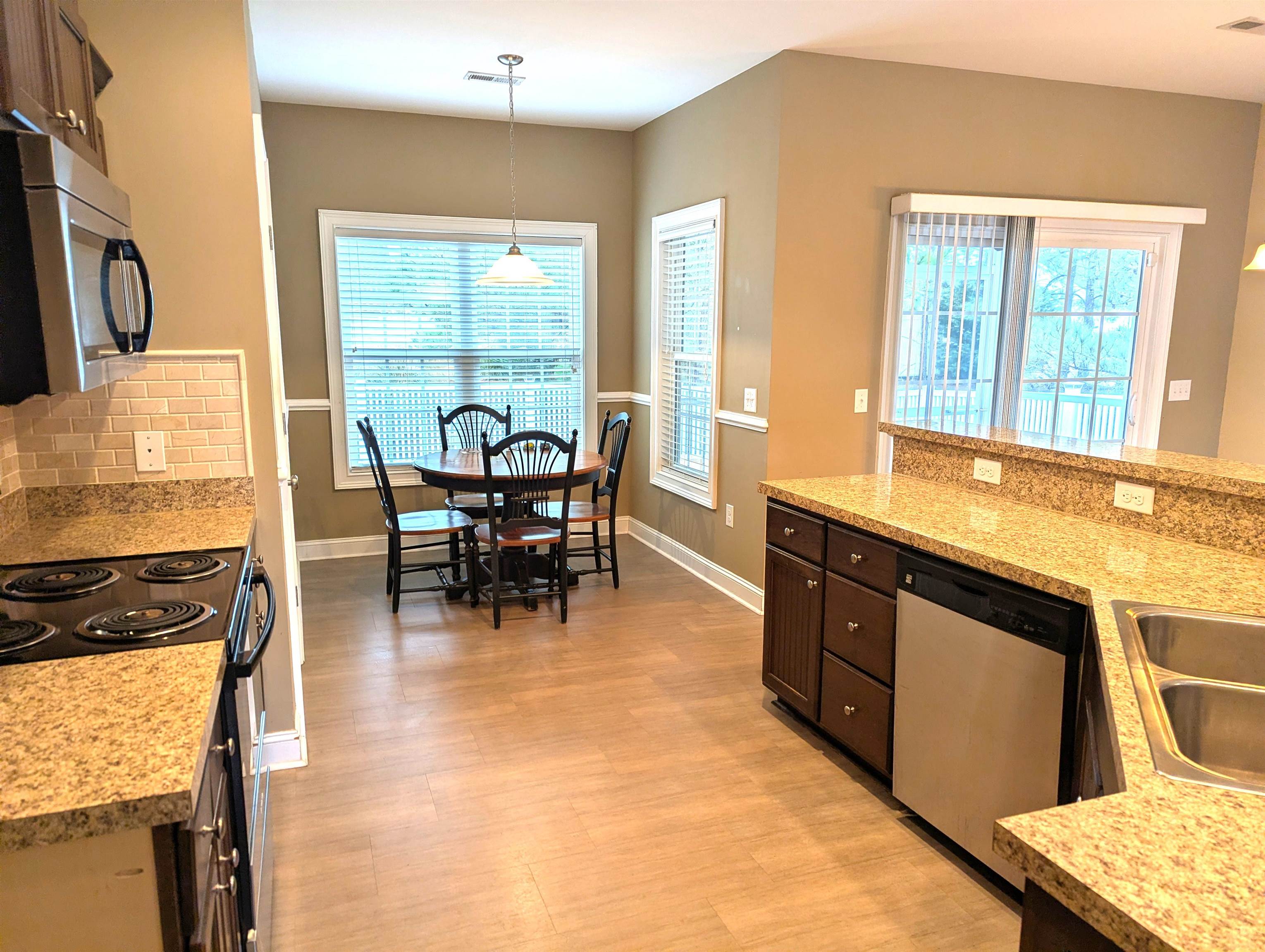 1100 Eureka Trail Longs, SC 29568 - Photo 11 of 40 Kitchen with appliances with stainless steel finishes, pendant lighting, decorative backsplash, light wood-type flooring, and light stone counters