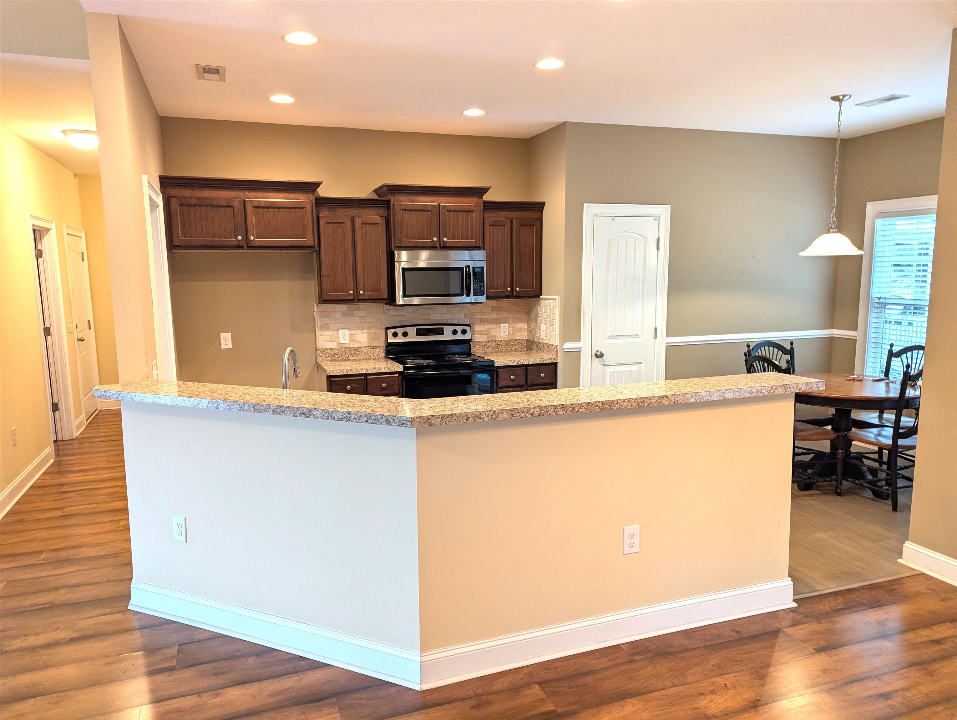 1100 Eureka Trail Longs, SC 29568 - Photo 9 of 40 Kitchen featuring decorative backsplash, electric range, stainless steel microwave, dark brown cabinetry, and light stone countertops