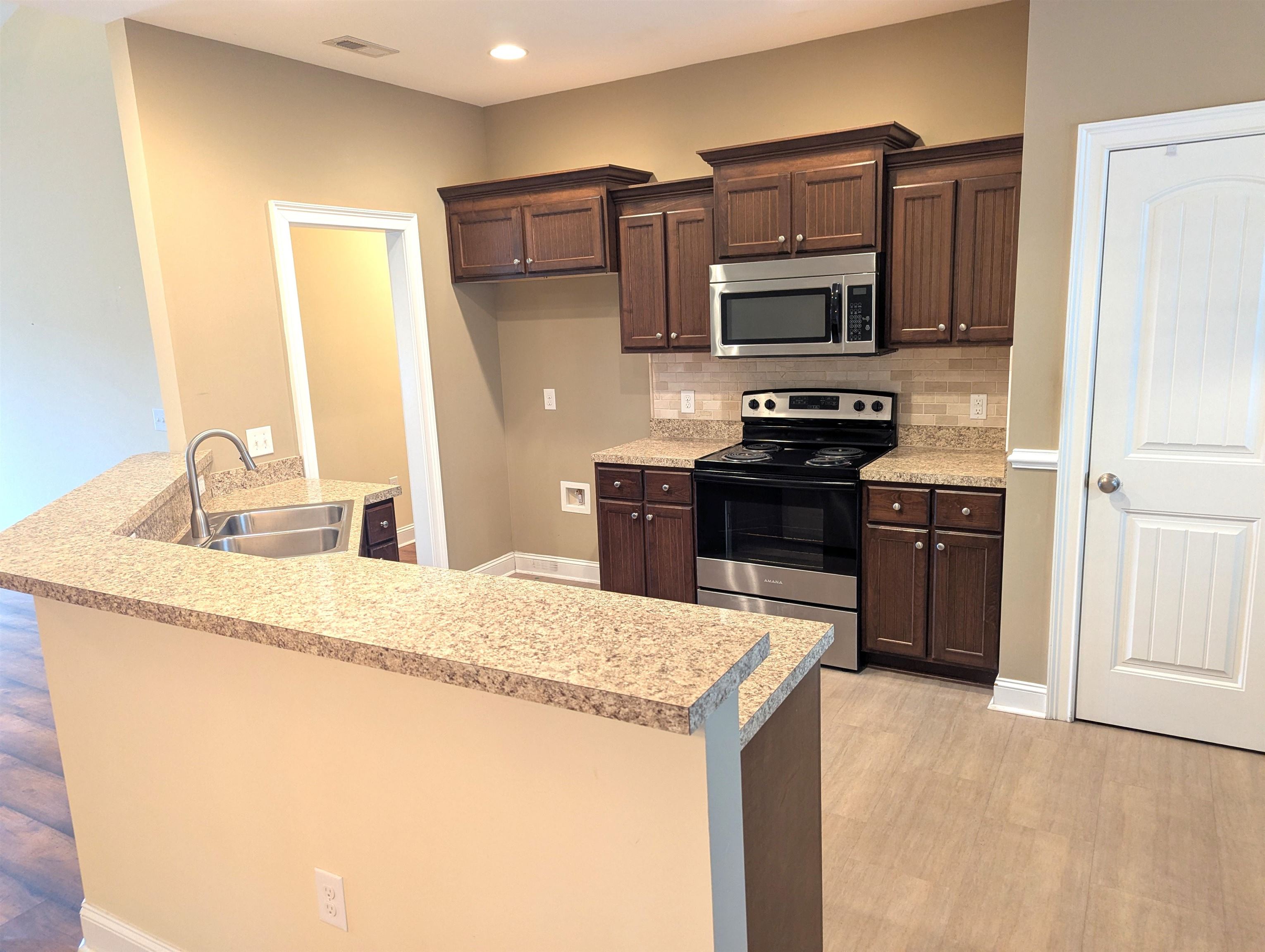 1100 Eureka Trail Longs, SC 29568 - Photo 10 of 40 Kitchen featuring a peninsula, appliances with stainless steel finishes, dark brown cabinets, backsplash, and recessed lighting
