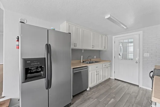 a kitchen with stainless steel appliances a refrigerator a sink and white cabinets