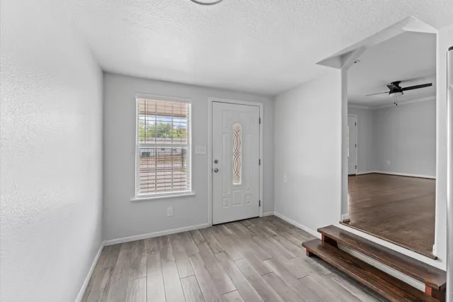 an empty room with wooden floor and windows