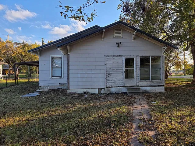 a backyard of a house with plants and large tree