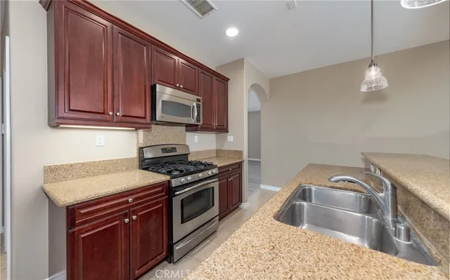 a kitchen with granite countertop a stove sink and microwave