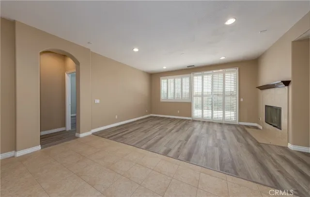 wooden floor in an empty room with a fireplace and a window