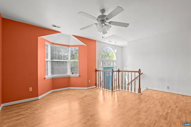 an empty room with chandelier fan and windows