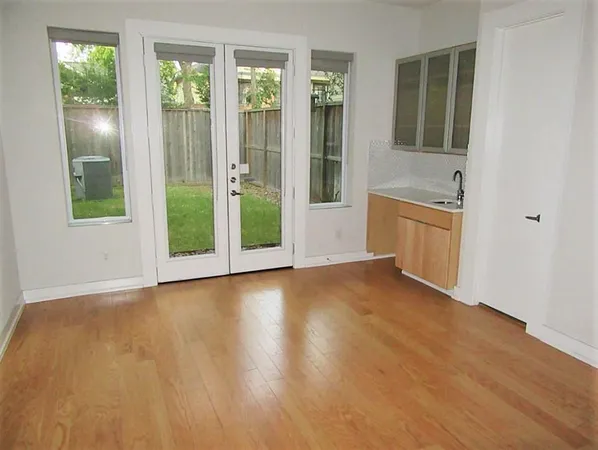 a view of an empty room with window and wooden floor