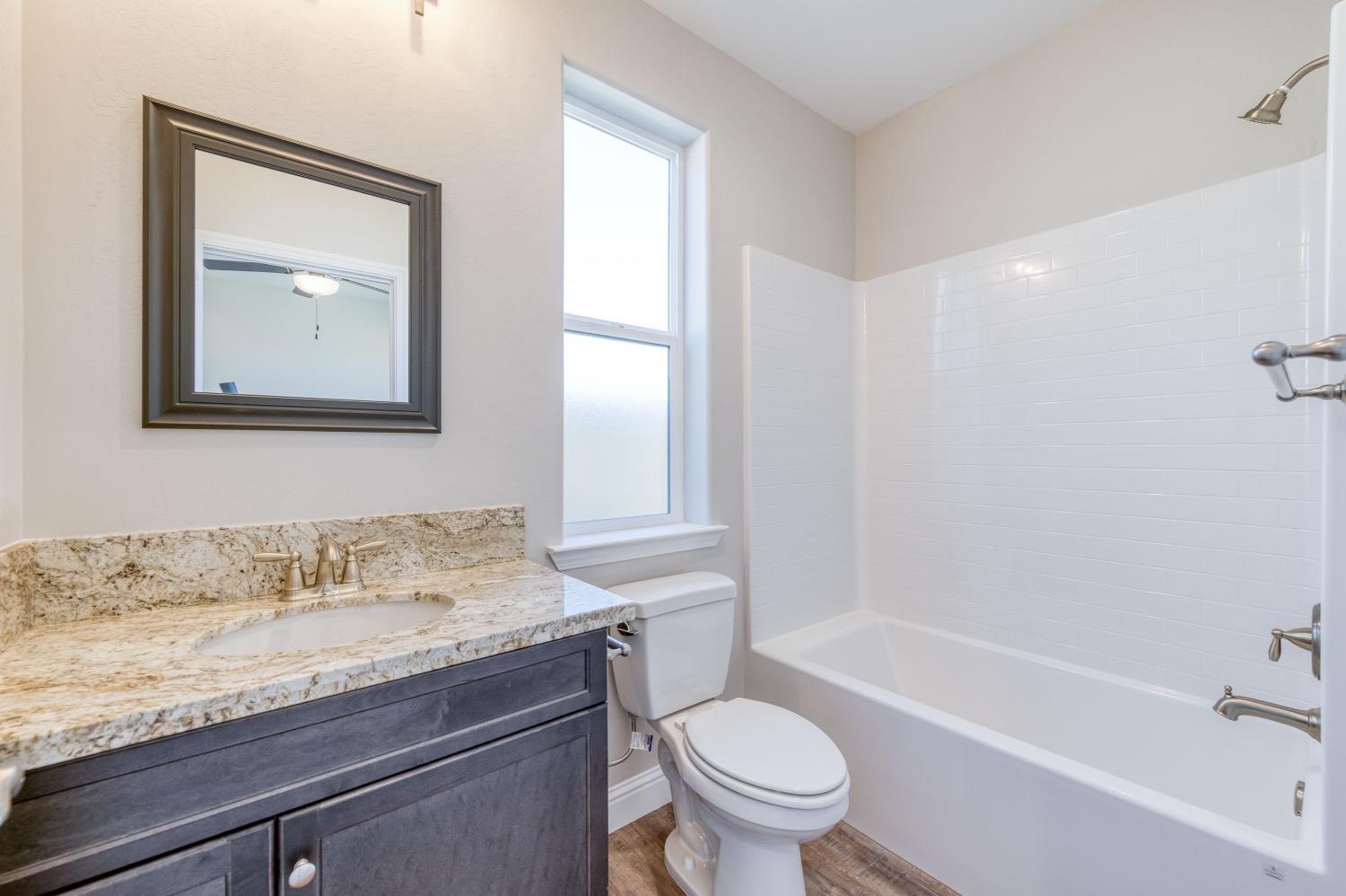 778 Shasta Street Madera, CA 93638 - Photo 16 of 28 a bathroom with a granite countertop sink toilet and shower