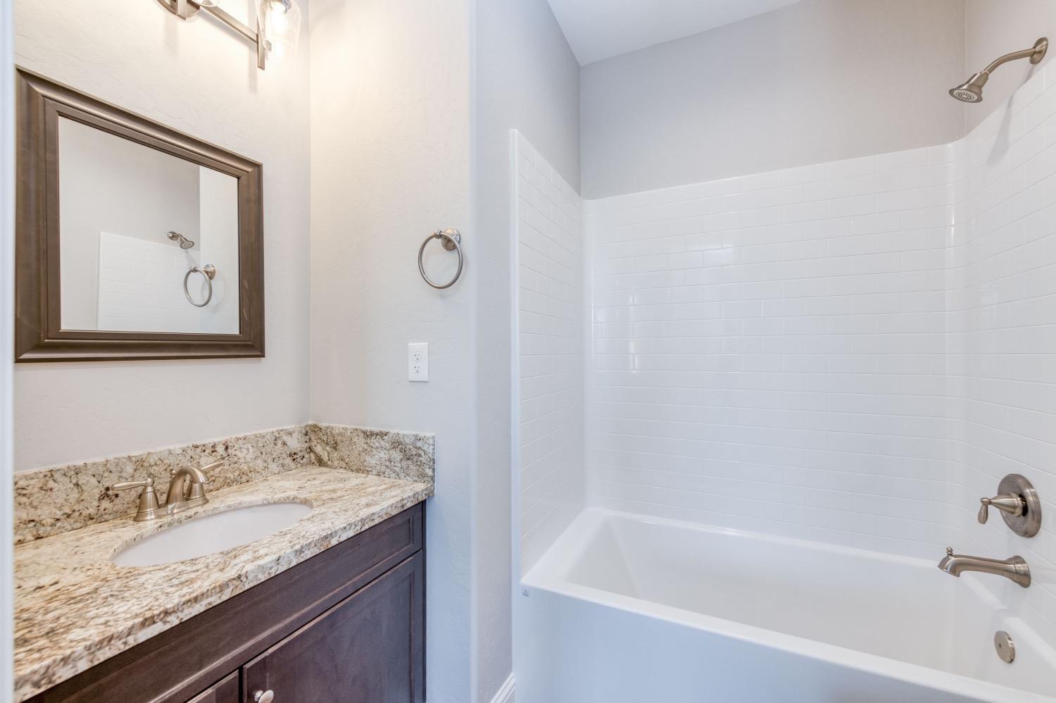 778 Shasta Street Madera, CA 93638 - Photo 17 of 28 a bathroom with a granite countertop sink and a bathtub