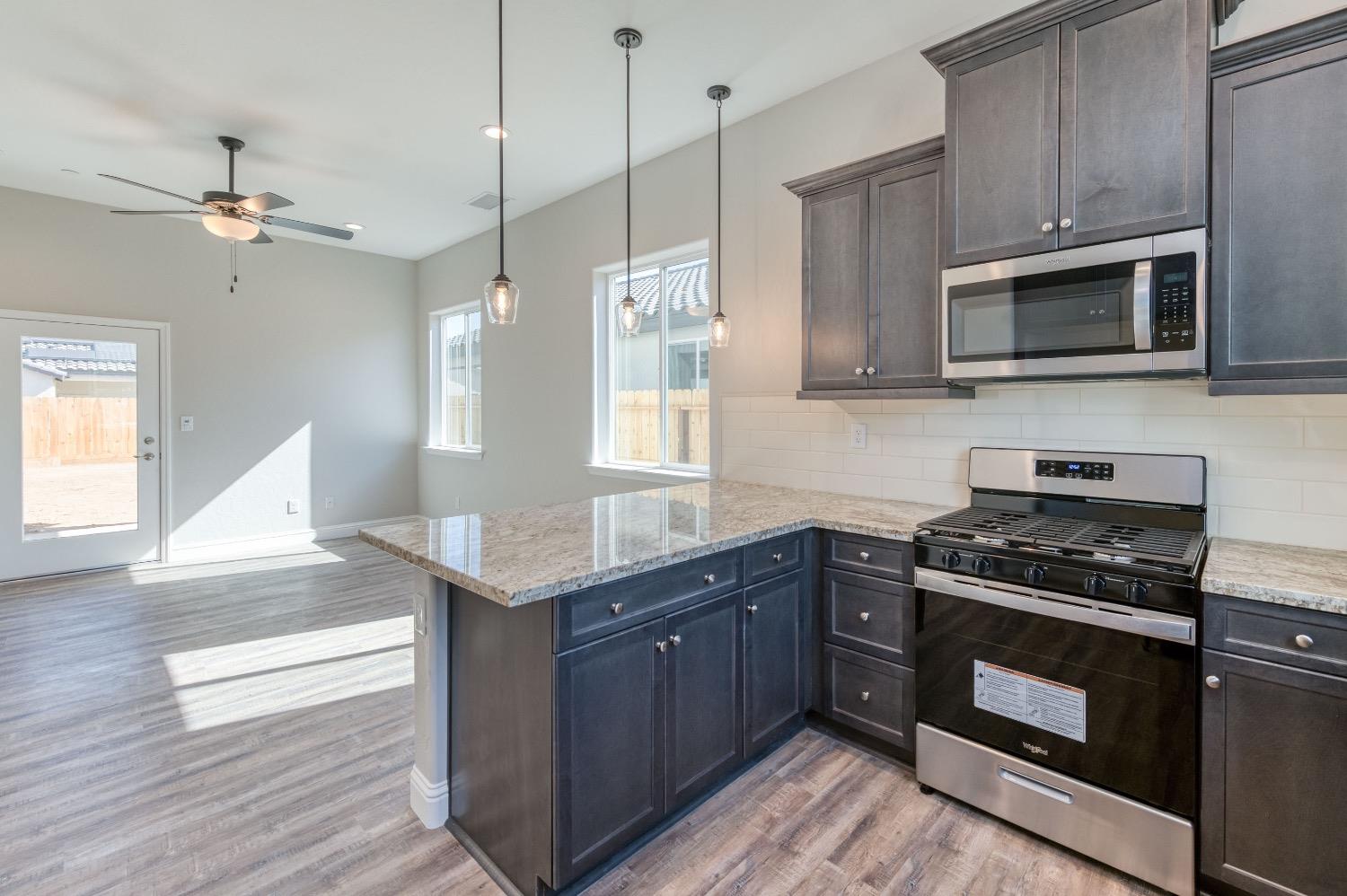 778 Shasta Street Madera, CA 93638 - Photo 8 of 28 a kitchen with stainless steel appliances granite countertop a stove a microwave and a wooden cabinets