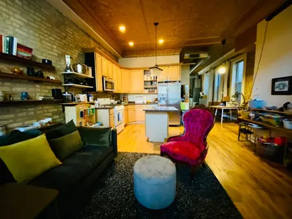 a living room with furniture kitchen view and a large window