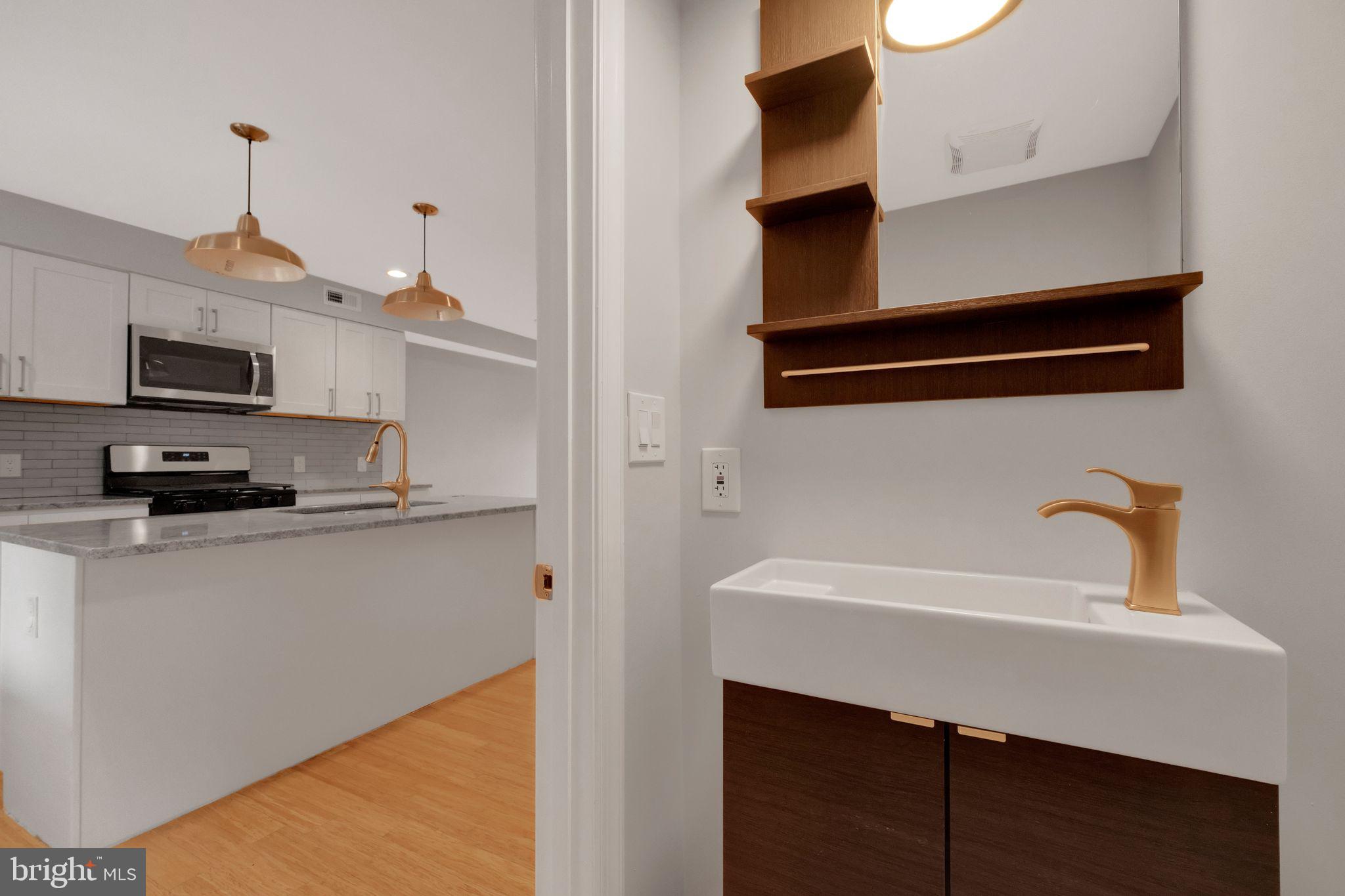 245 South Clinton Street Baltimore, MD 21224 - Photo 13 of 39 a kitchen with a sink a microwave and cabinets