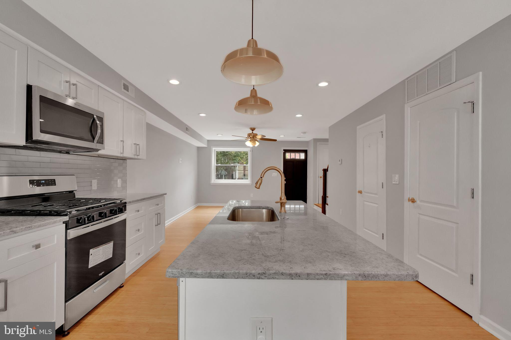 245 South Clinton Street Baltimore, MD 21224 - Photo 6 of 39 a kitchen with kitchen island granite countertop stainless steel appliances a stove sink and microwave