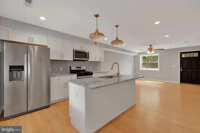 a kitchen with stainless steel appliances granite countertop a sink a stove top oven a counter space and cabinets