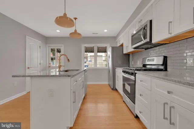 a kitchen with stainless steel appliances granite countertop a sink a stove and a refrigerator