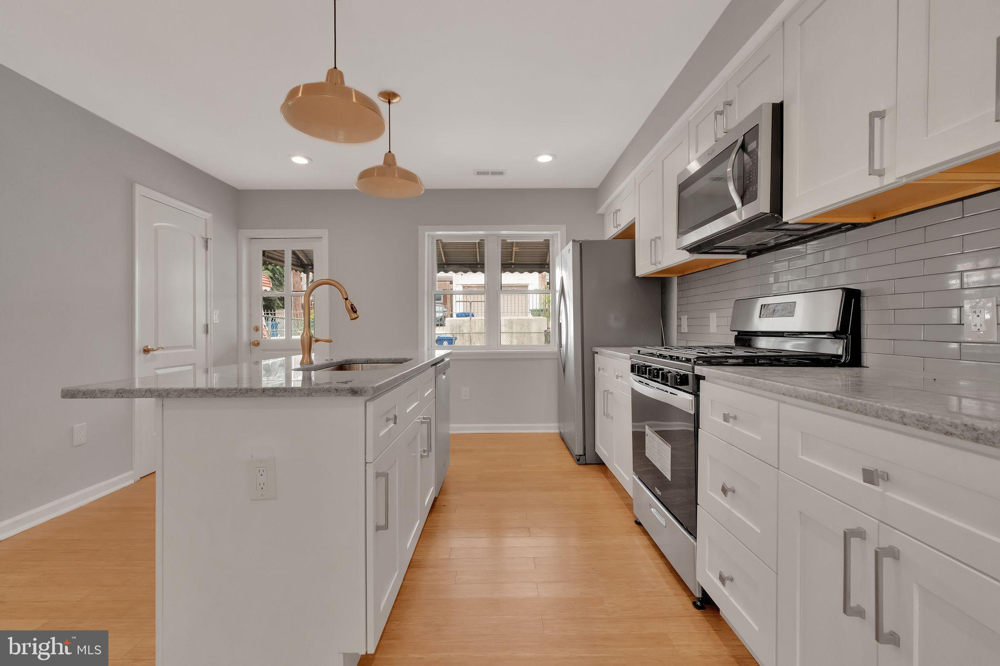 245 South Clinton Street Baltimore, MD 21224 - Photo 9 of 39 a kitchen with stainless steel appliances granite countertop a sink a stove top oven a counter space and cabinets
