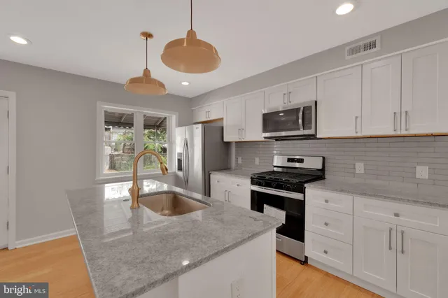 a kitchen with stainless steel appliances granite countertop a sink a stove a refrigerator a center island a stove cabinets and a dining table