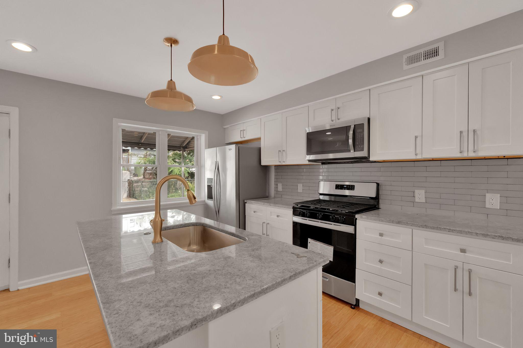 245 South Clinton Street Baltimore, MD 21224 - Photo 10 of 39 a kitchen with stainless steel appliances granite countertop a sink a stove and a refrigerator