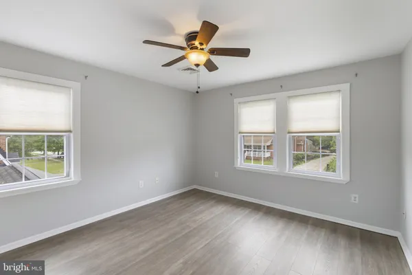 a view of an empty room with wooden floor and windows