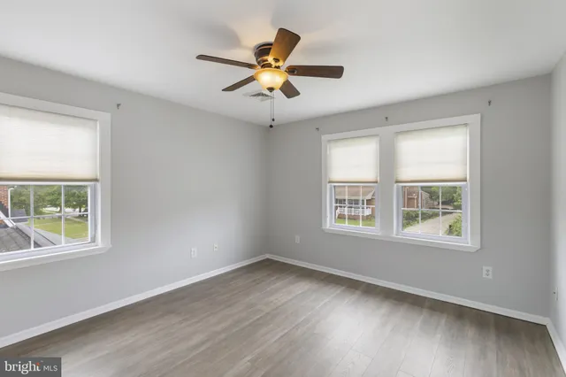 a view of an empty room with wooden floor and windows